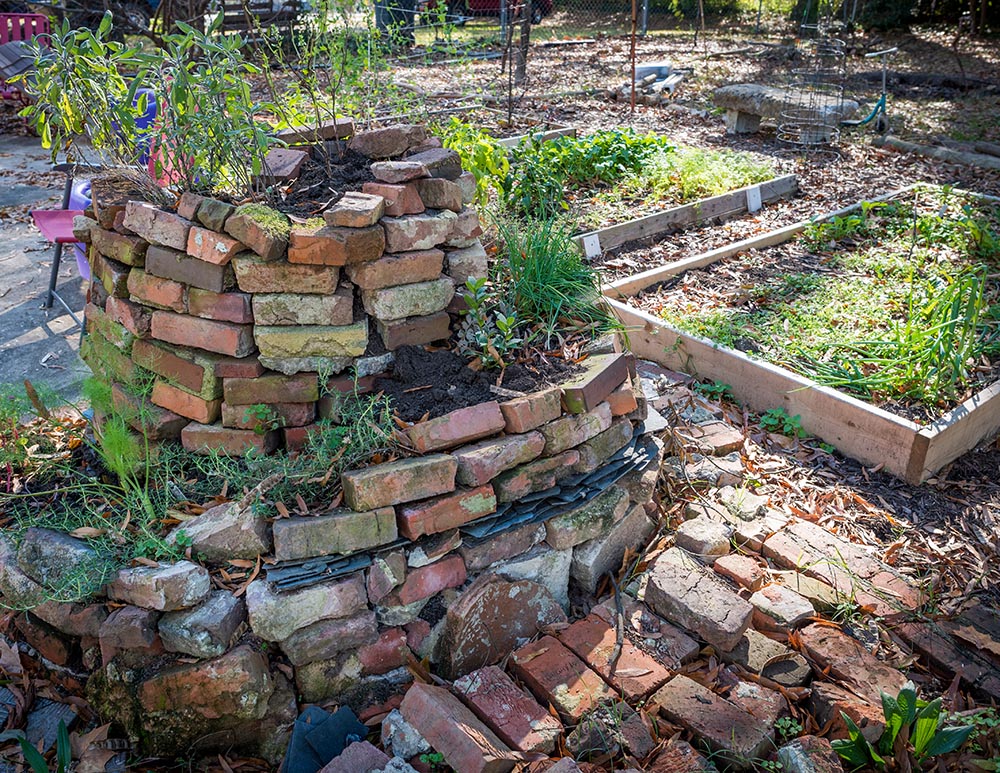 Brick herb spiral with raised garden beds in the background